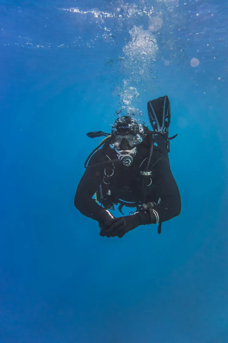 Scuba diver underwater in clear blue water during a recreational dive.